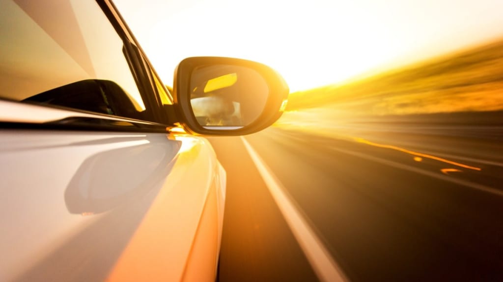 A car driving on a highway at sunset.
